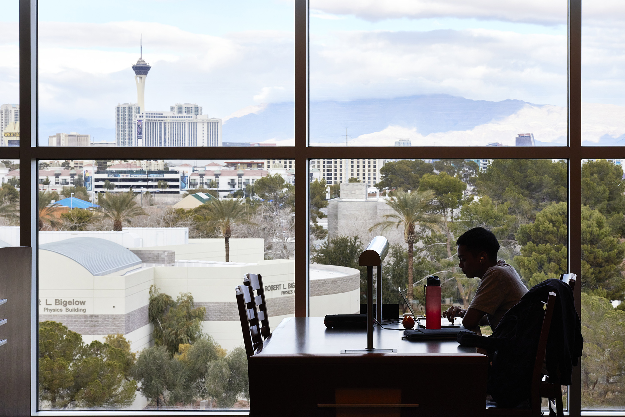 Student studies in front of a large window with the Stratosphere tower visible in the background.