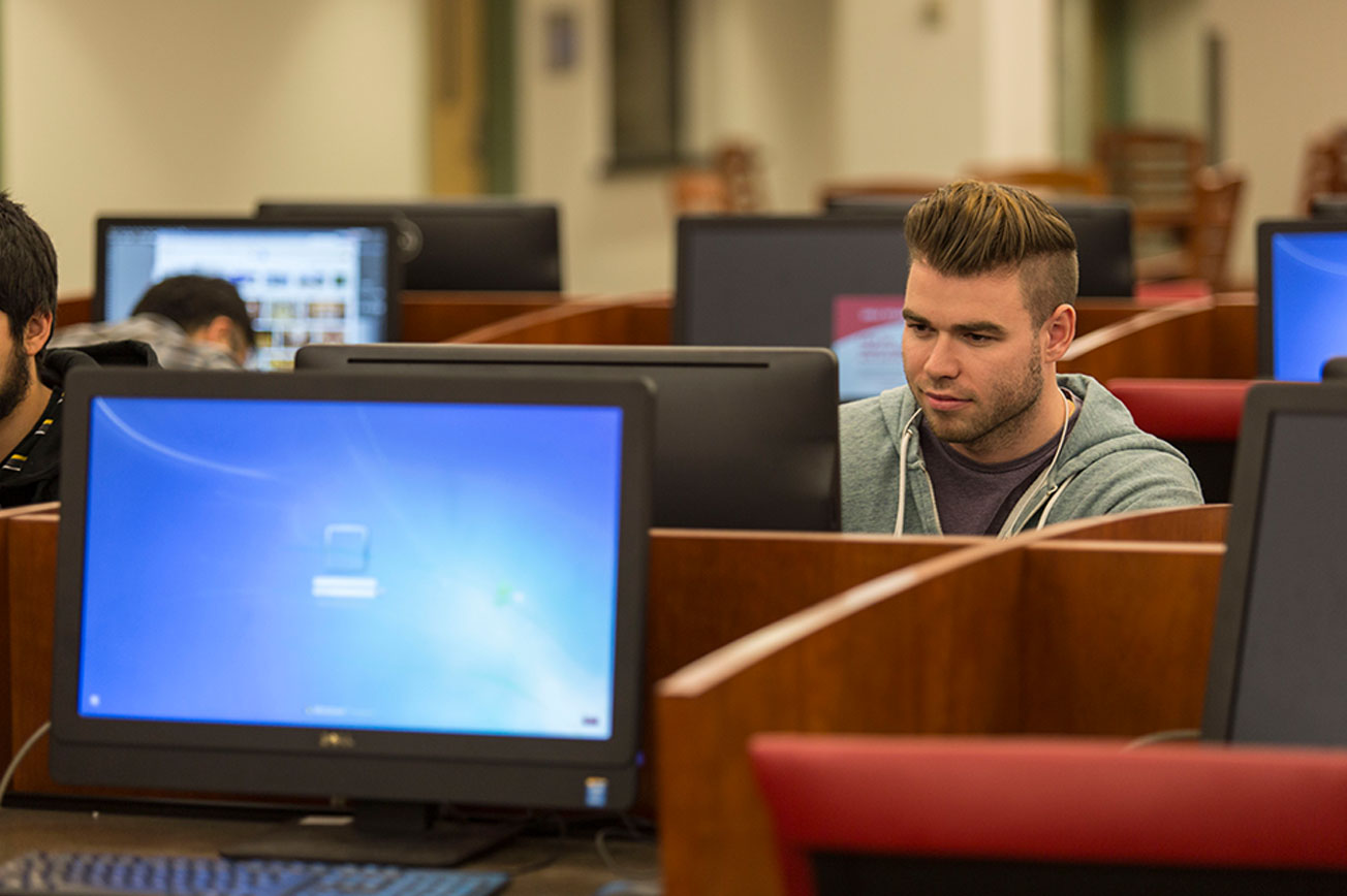 A male student stares intently at a computer screen.