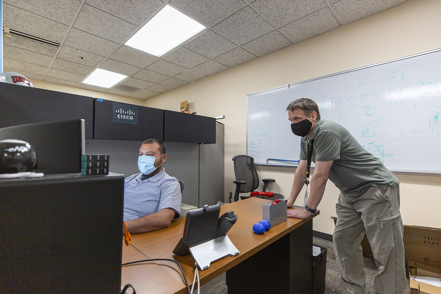 Two staff members gaze at a computer monitor.