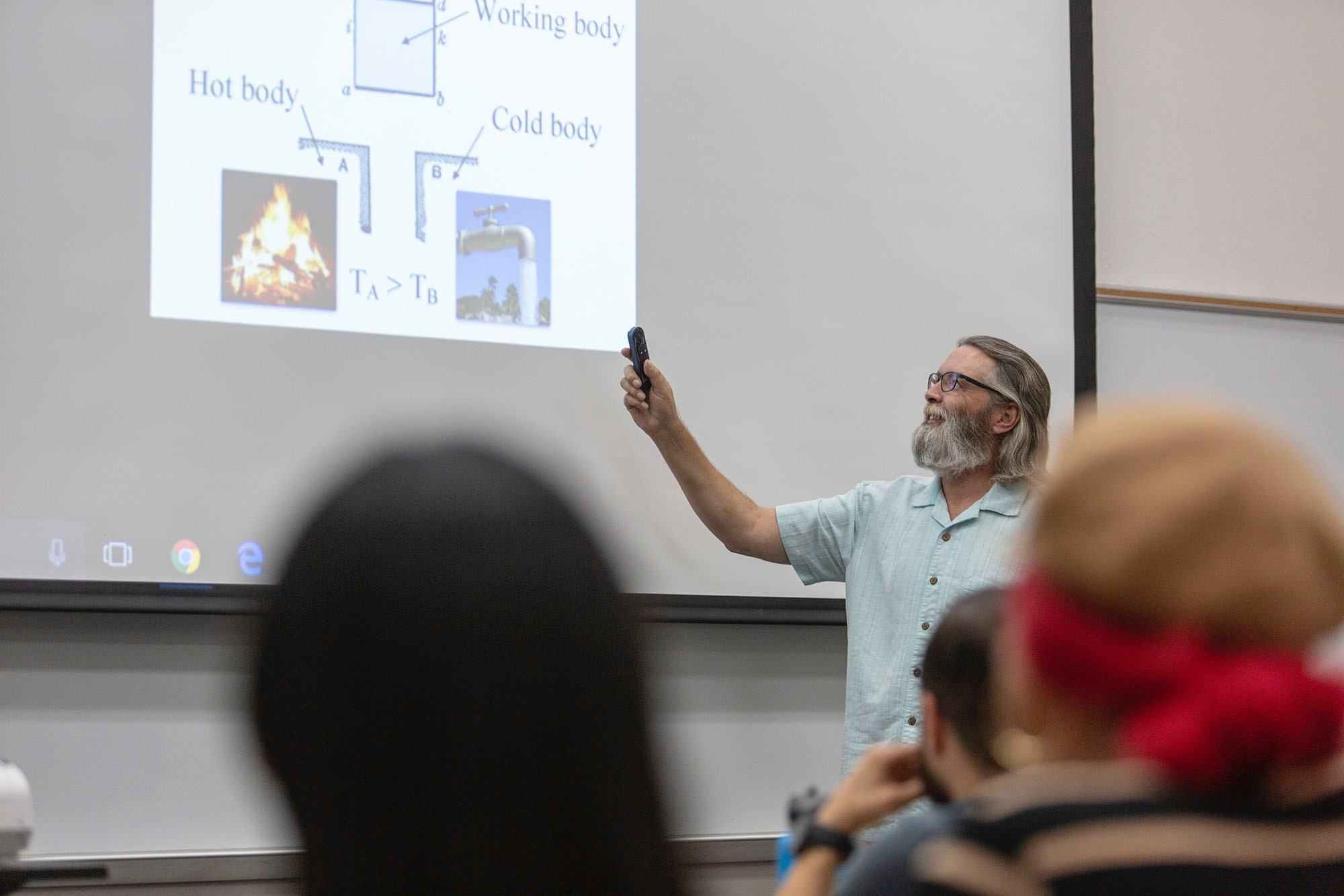 A male instructor points at a projector screen.