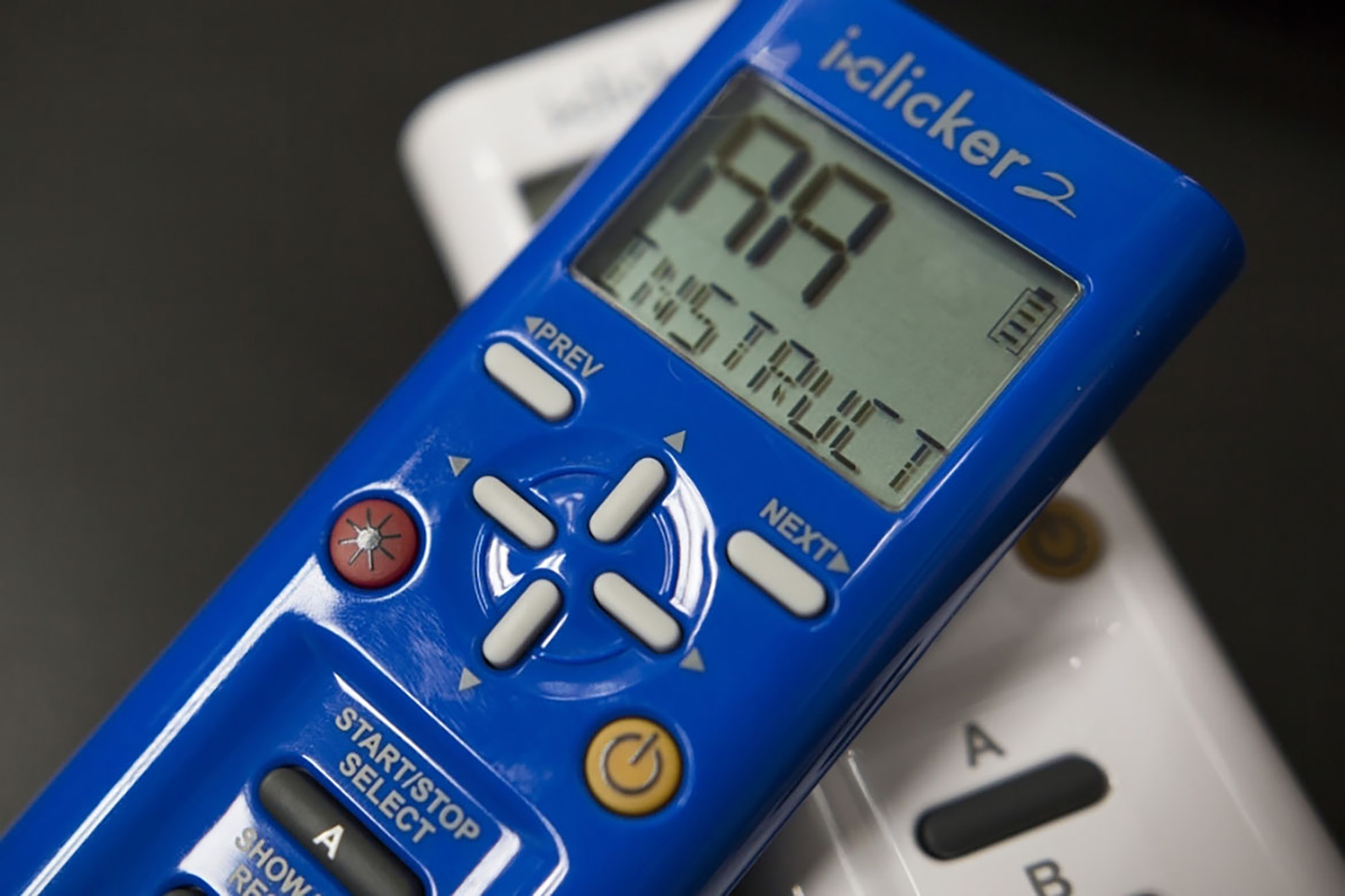 A blue clicker laying on top of a white clicker.