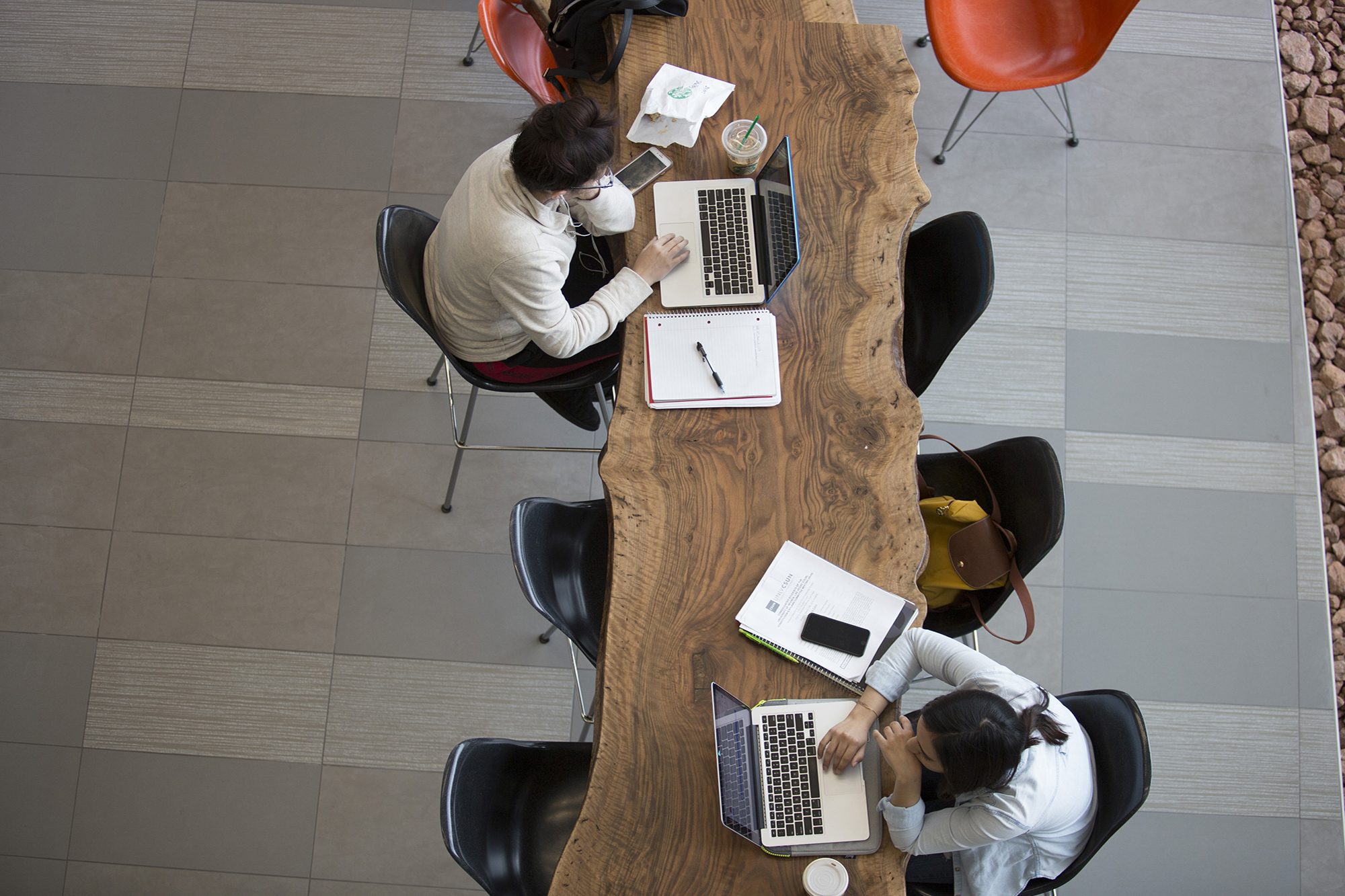 Aerial view of students studying at a long wooden table.