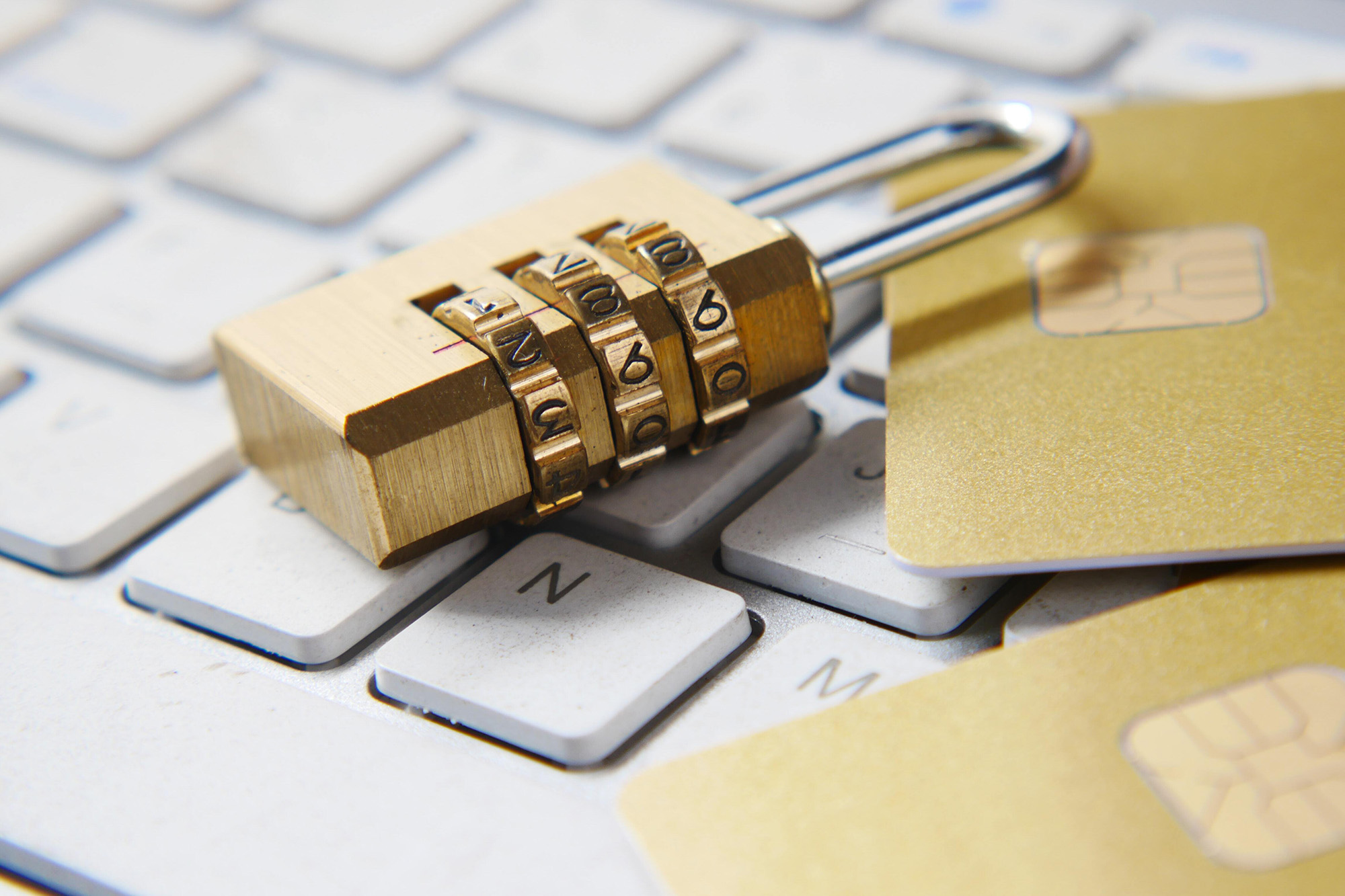 A brass dial combination lock laying on a white keyboard.