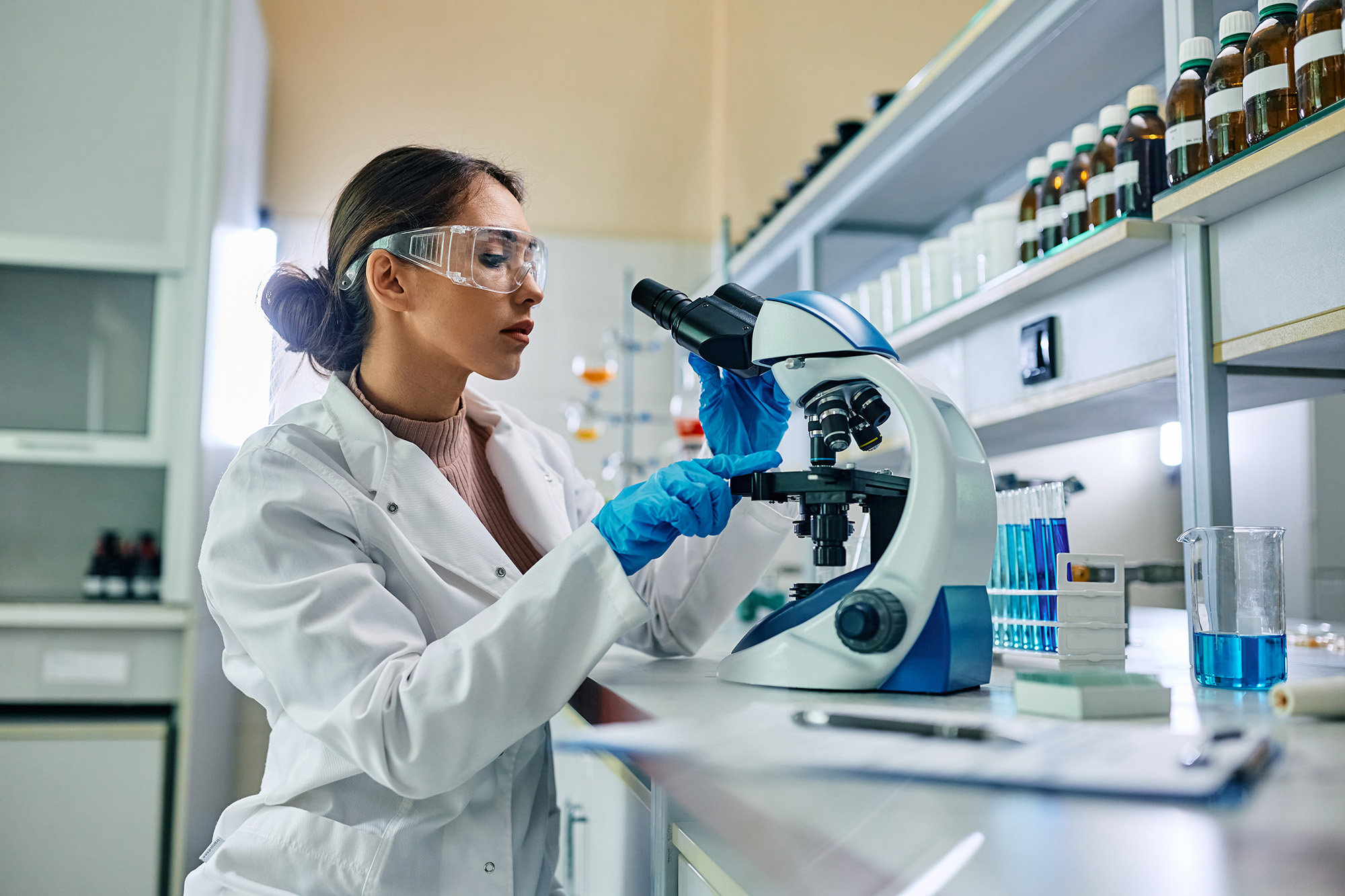 A biochemist using microscope while working on scientific research in laboratory.