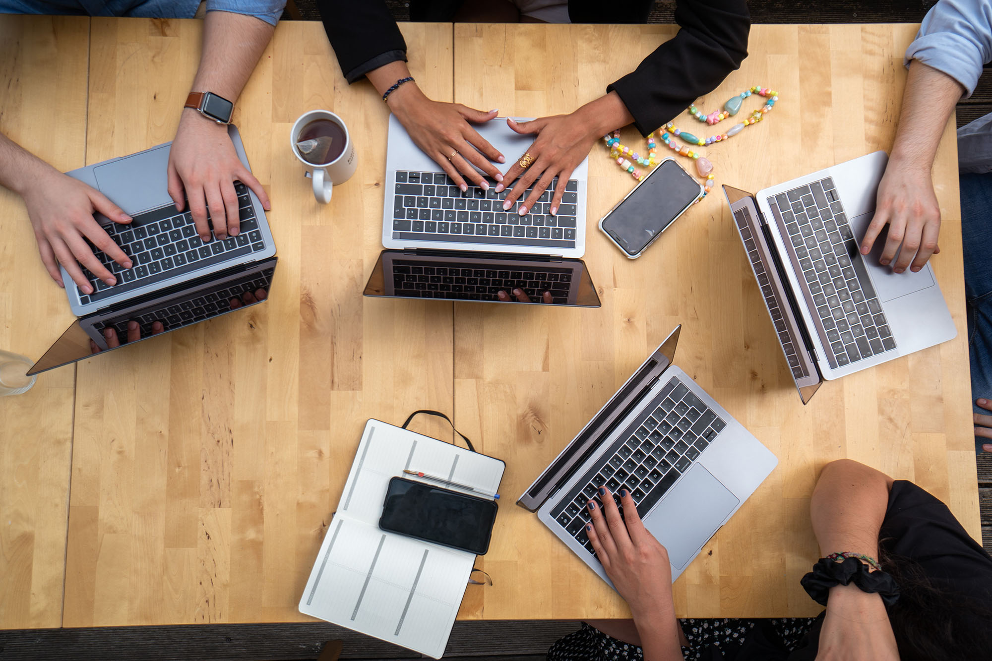 Four open laptops with hands typing.