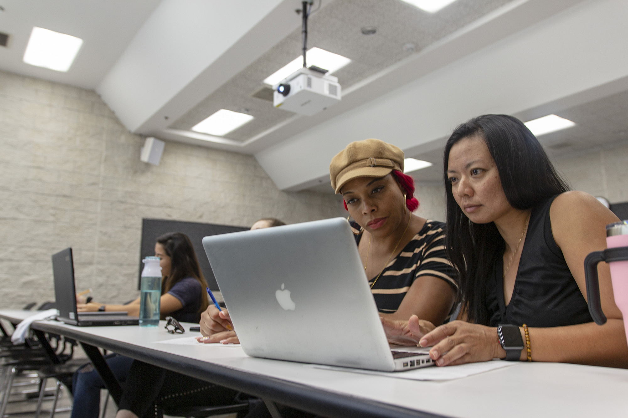 Two female staff members gaze at a laptop screen.