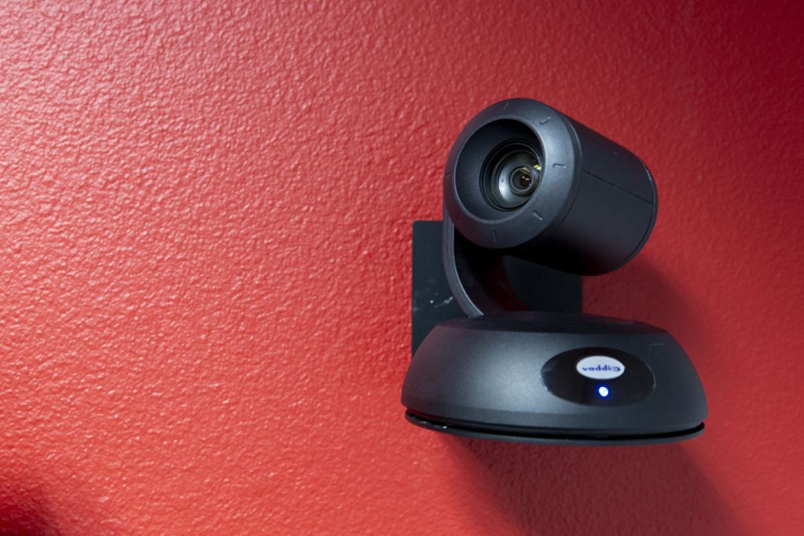 Close shot of a lecture capture camera mounted on a red wall