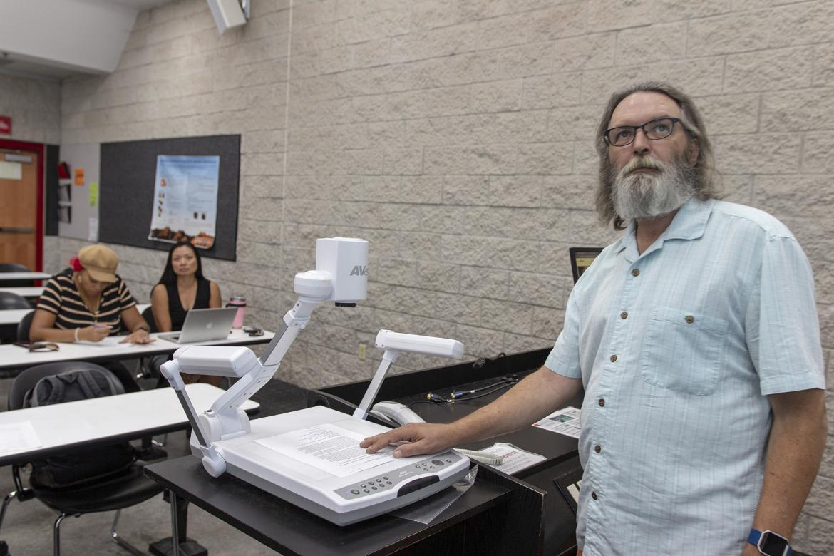 A male U-N-L-V staff member standing at a teaching podium.