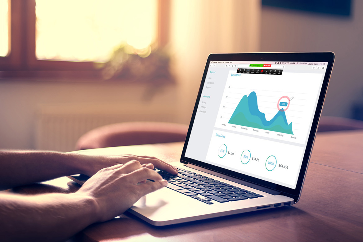 Hands typing on a keyboard of a laptop displaying a graph.