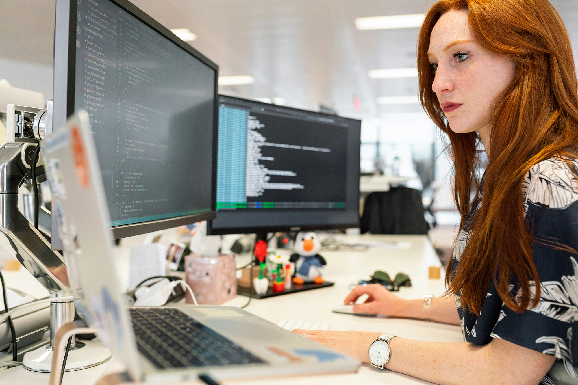 A person clicking a mouse at a multi screen workstation.