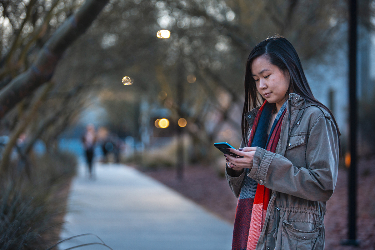 A female student peers down at her mobile device.