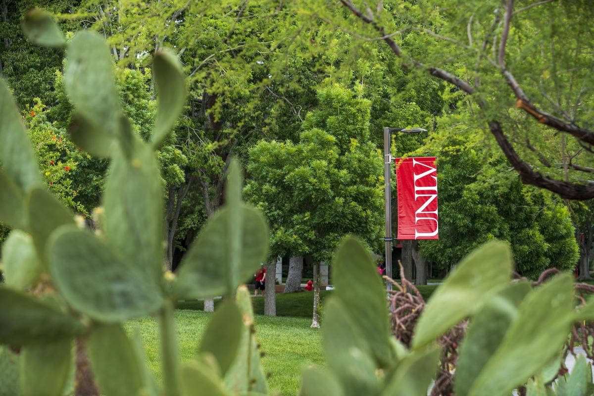 A red UNLV banner amidst lush, green foliage.