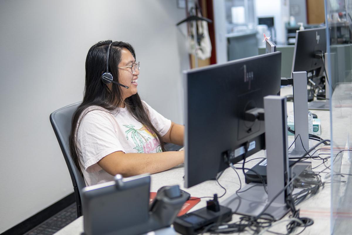 Person wearing a headset at a help desk terminal.