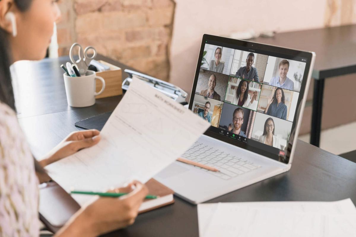 Person holding a paper during a laptop Zoom call.