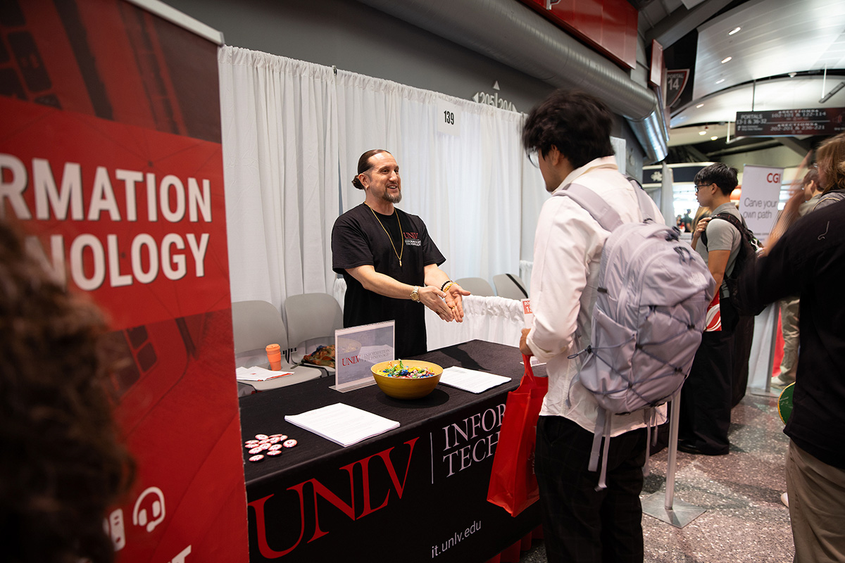 University community members connecting at campus resource table. 