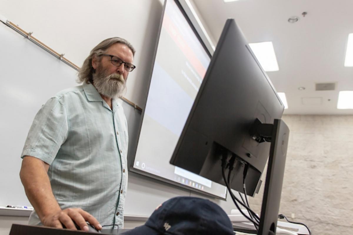 A male U-N-L-V staff member standing at a teaching podium.