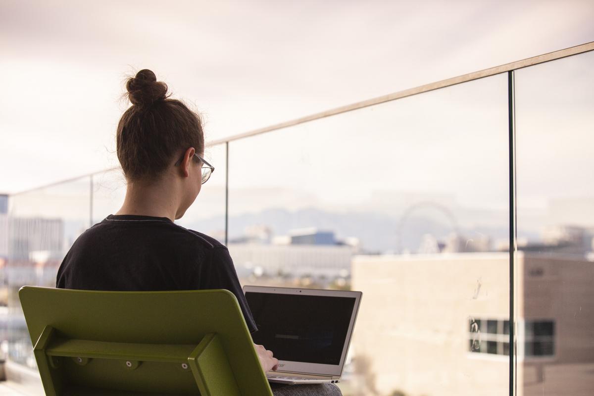 Over-the-shoulder view of a female student outdoors on her laptop.