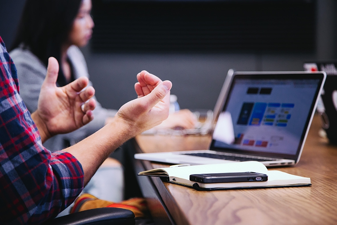 Close shot of hands gesturing in front of a lap top.