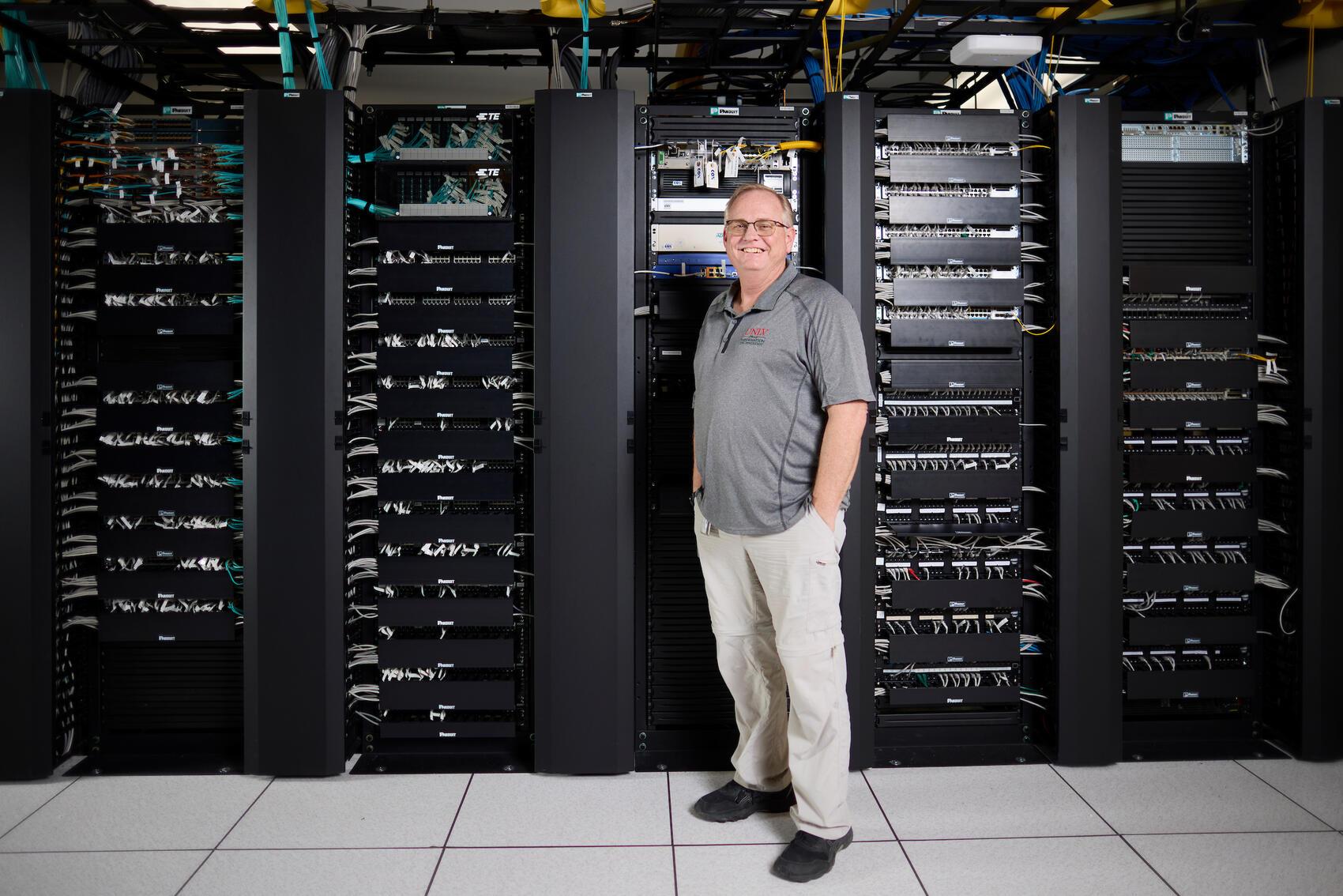 Man standing in front of black data servers.
