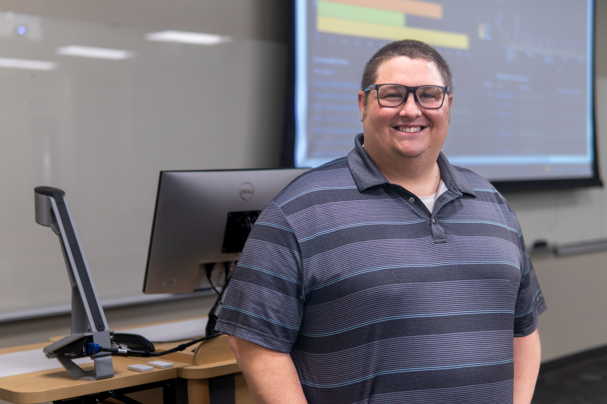 Person standing in front of classroom lectern.