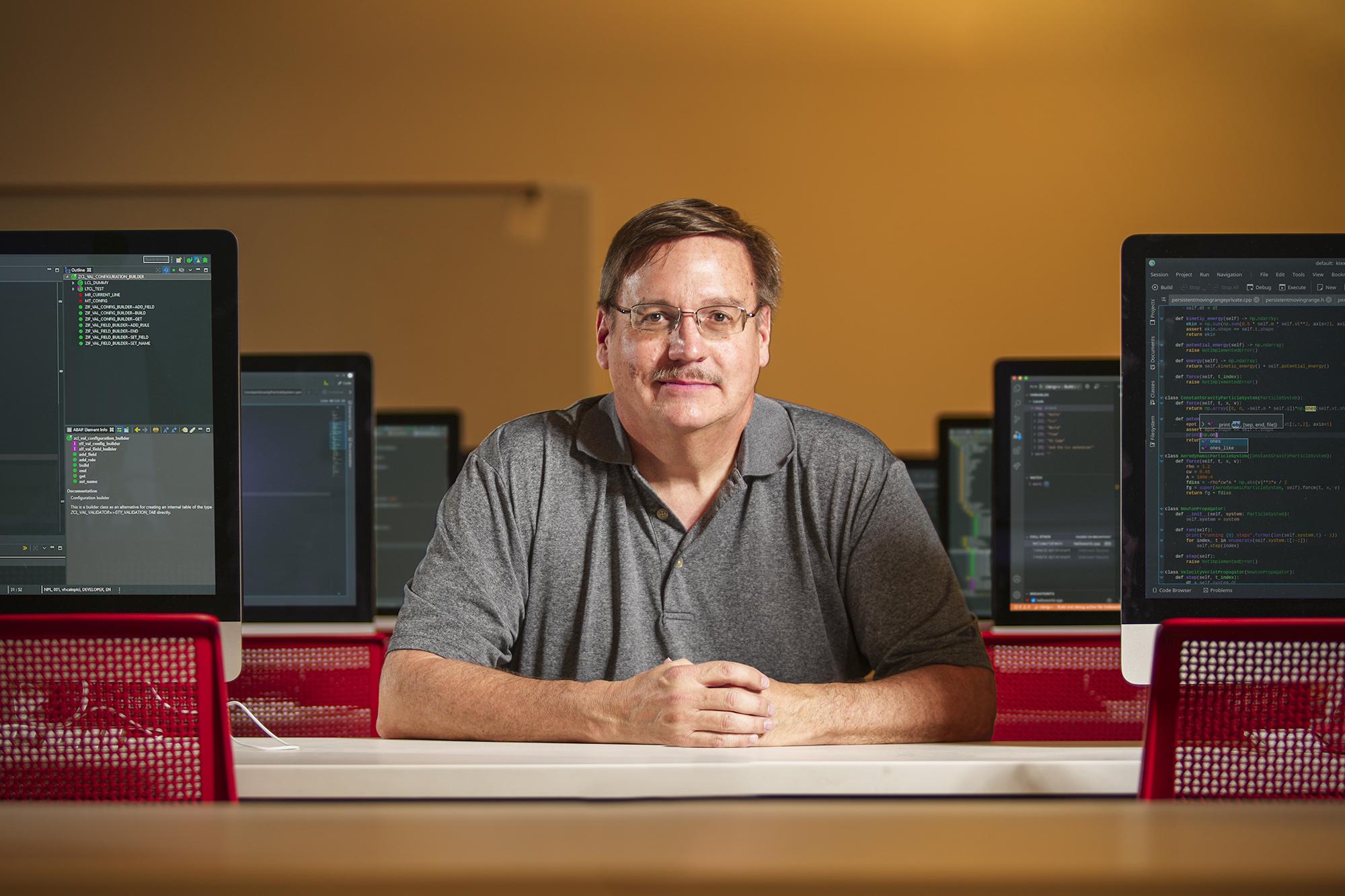 Two rows of computers with person sitting in middle