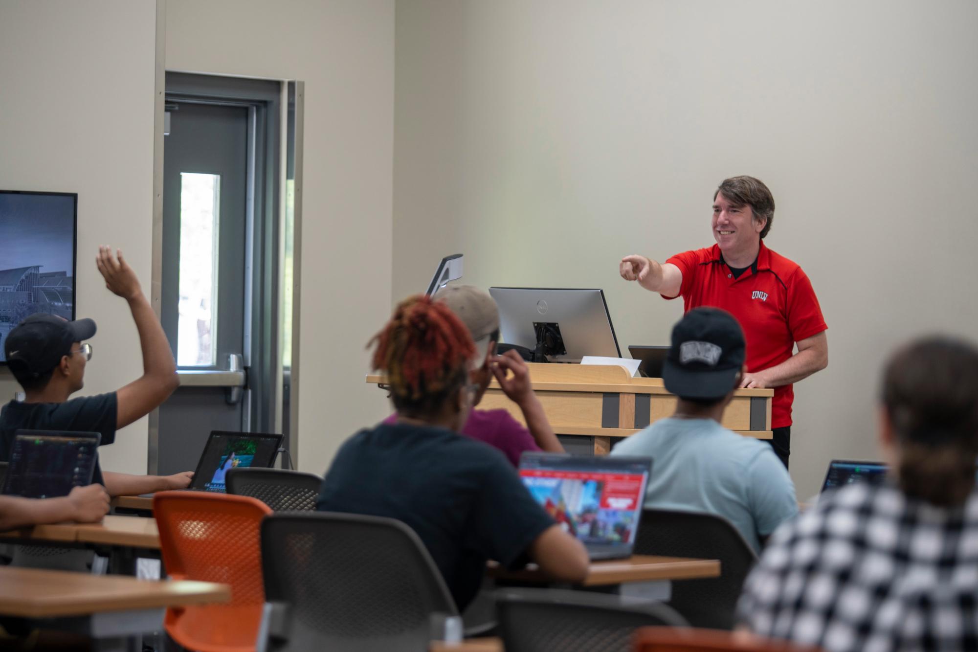Instructor calling on a student with their hand raised.