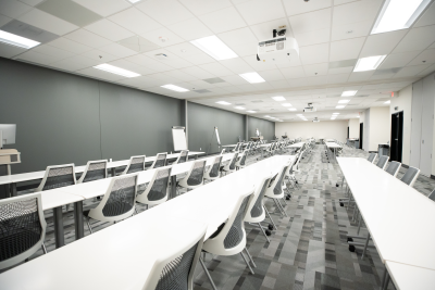 Large classroom with white desks and chairs that separates into three different classrooms.