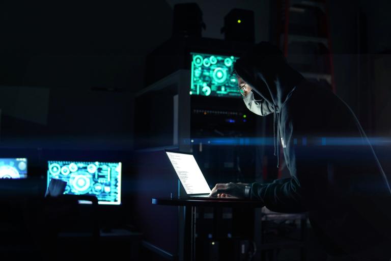 Person using laptop computer in dark room, cybersecurity awareness month