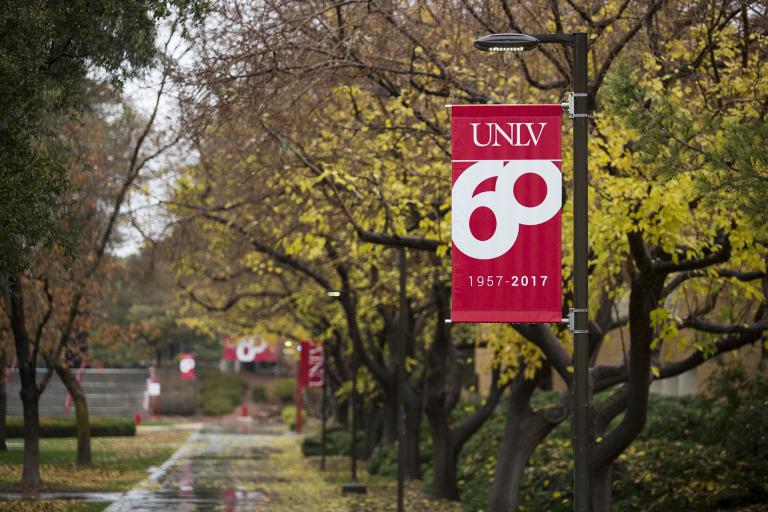 A red U-N-L-V banner hangs over a rain-moistened pathway.