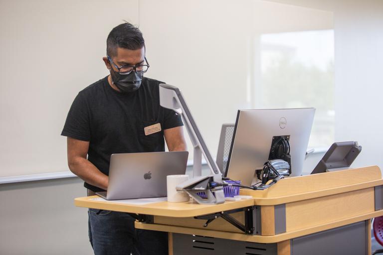 Instructor using laptop at lectern in a technology enhanced classroom.