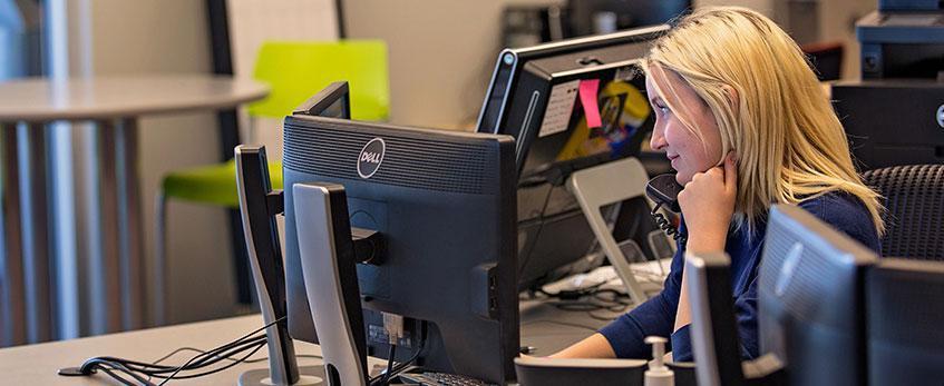 A female student employee fields calls at a U-N-L-V help desk.