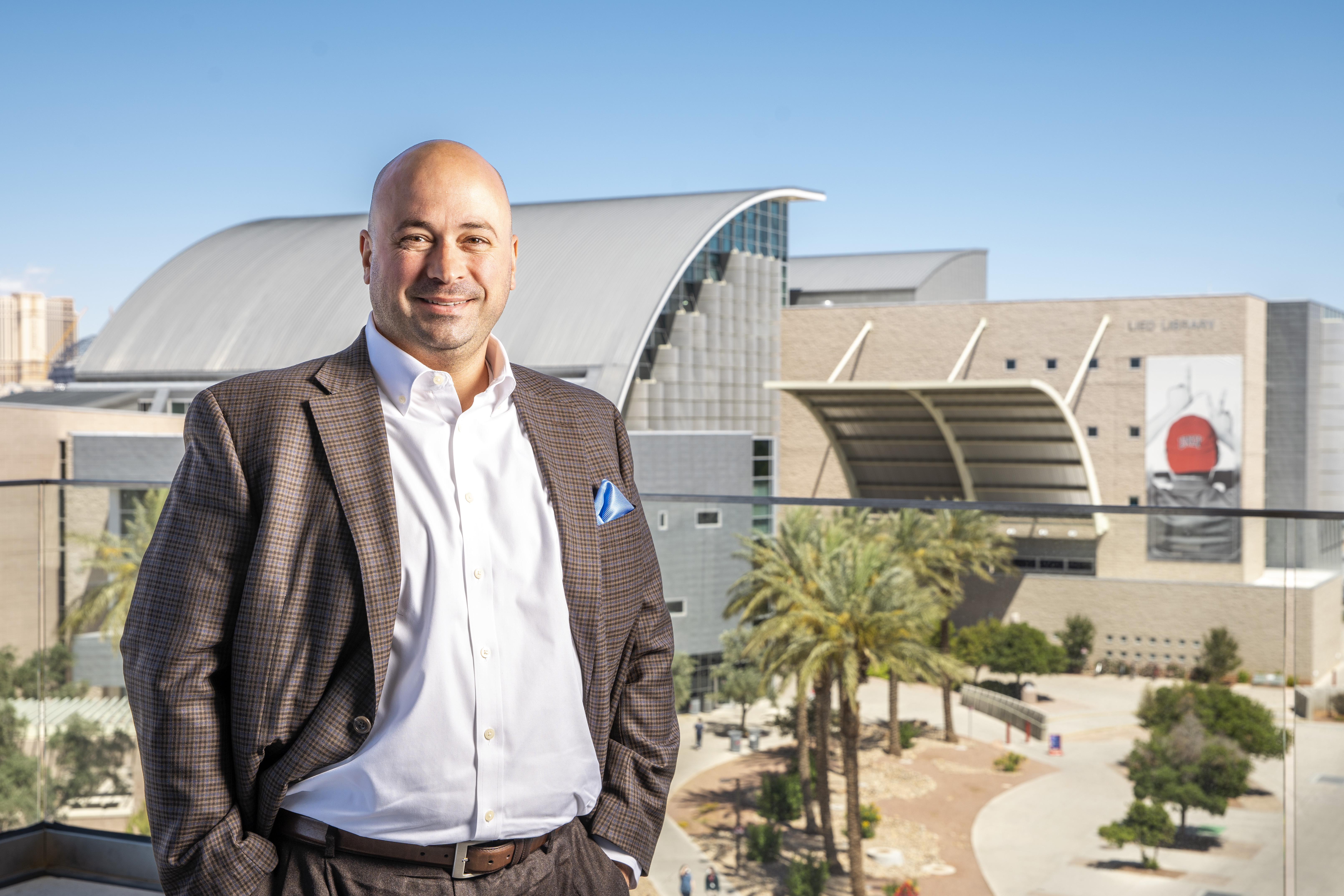 Person standing with hands in pockets with building in background